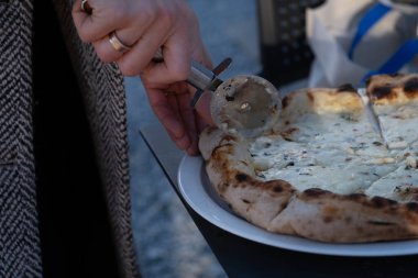 Close up of a freshly baked white pizza being cut with a pizza cutter. The melted cheese and thyme toppings create a rustic and appetizing scene. Perfect for use in food blogs, restaurant promotions clipart