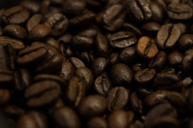 A macro shot of roasted coffee beans showcasing their texture and rich brown color. Ideal for coffee shop promotions, beverage advertisements, or culinary content clipart