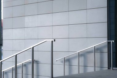 Minimalist modern bina cephesine karşı parlak metal bir merdiven. Basitlik, mimari ve kentsel ortam temaları için mükemmel