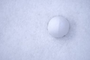 A perfectly rounded snowball resting on a smooth snow surface, capturing the essence of winter fun and playful outdoor activities. The clean, white backdrop enhances the focus on the snowball, ideal clipart