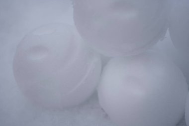 A detailed close up of smooth snowballs featuring smiley impressions, arranged artistically against a snowy background. The subtle texture of snow is emphasized, creating a serene and playful winter clipart