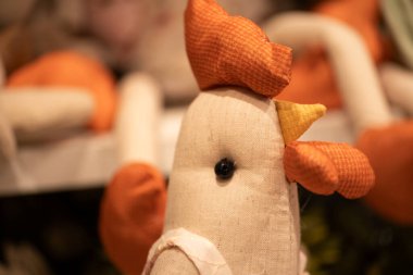 Turuncu ve bej tonlu el yapımı bir horoz oyuncağı. Pofuduk oyuncakta detaylar ve bir düğme göz var. Sade ve sade bir estetik veriyor. İlgili temalar için mükemmel