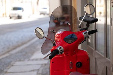 Polonya 'nın Wroclaw şehrinde sakin bir kaldırım taşı caddesinde, şeffaf bir ön camı ve krom aynaları olan kırmızı bir scooter' ın yakın çekimi. Kentsel hareketlilik, ulaşım ve seyahat temalı tasarımlarda kullanım için ideal