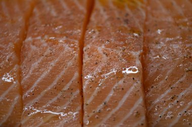 Yağlı ve karabiberli çiğ somon filetosu. Yemek blogları, deniz ürünleri ürünleri promosyonları, restoran menüleri ve beslenme içeriği için ideal. Tazeliği, omega-3-zengini malzemeleri ve aşçılık için yüksek kaliteli proteini vurgular.