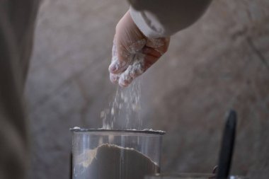 Küçük bir çocuk mutfakta yardım ederken şeffaf bir kabın içine un serpiyor. Bu yakın çekim, evde pişirme etkinliği sırasında duyusal olarak zengin bir anı yakalıyor. Aile yemeklerini, çocuk gelişimini veya eğitici gıda içeriğini resmetmek için ideal