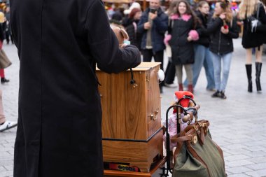 Wroclaw, Polonya 'daki bir Noel pazarında geleneksel fıçı org çalan bir sokak müzisyeni. Ahşap enstrüman, şenlikli süslemeler ve neşeli bir kalabalıkla çevrili, sıcak ve sıcak bir ortam yaratır.