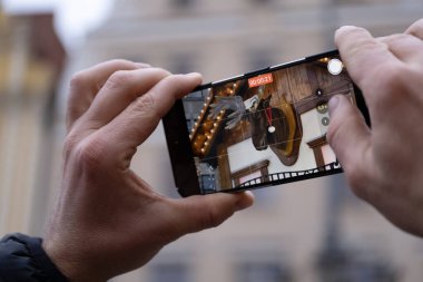Akıllı telefonu olan bir adam, Wroclaw, Polonya 'nın merkezindeki şenlikli Noel pazarının videosunu çekiyor. Arka plan süslemeler, çelenkler ve aydınlık pazar tezgahlarıyla dolu. İdeal
