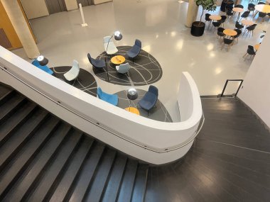 Çağdaş ofis ya da üniversite salonu aşağıda yuvarlak bir oturma odası ve siyah merdivenleri var. Mekanda modern mobilyalar, parlak ışıklandırma ve minimal tasarım yer alıyor. Başlıklar için ideal