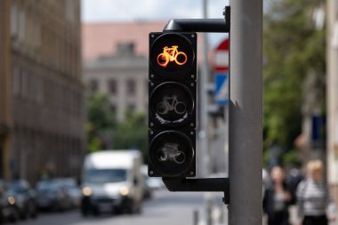 Şehir kavşağındaki bisikletlere kırmızı trafik ışığı. Bisikletçilere durmaları için işaret veriyor. Modern şehirlerdeki bisiklet altyapısını ve güvenliğini gösteren detaylı bir sokak manzarası. Ulaşım ve hareketlilik temaları için kullanışlı.