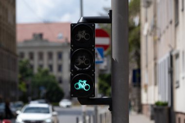 Şehir caddesindeki bisikletçiler için ayrılmış bir trafik lambasında yanan yeşil bisiklet sinyali. Kentsel bisiklet altyapısı güvenli ve çevre dostu ulaşımı destekliyor. Hareketlilik ve ulaşım temaları için ideal.