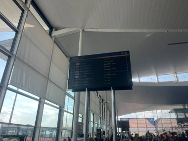 Wroclaw Nicolaus Copernicus Havaalanı 'ndaki elektronik kalkış panosu, Mayıs 2025, uçuş bilgilerini terminalde gösteriyor. Fotoğraf, büyük cam pencereler ve gezginlerle modern iç mekanı yakalıyor.