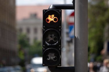 Kentsel bir çevrede özel bir trafik lambasında bisikletler için kırmızı sinyal. Parlayan bisiklet sembolü bulanık bir şehrin arka planında göze çarpıyor. Ulaşım ve bisiklet gibi konular için uygun