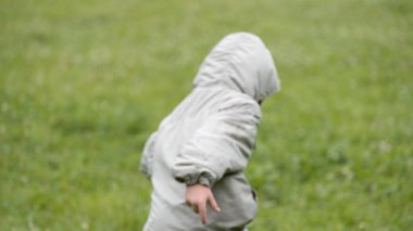 Açık gri kapüşonlu ceket giyen genç bir çocuk yemyeşil bir çim tarlasında oynarken arkadan yakalandı. Görüntü hareketlere ve çocukluk aktivitelerine odaklanıyor. Bu da onu açık hava eğlencesi, çocukluk anıları ve mevsimsel acti kavramlarına uygun kılıyor.