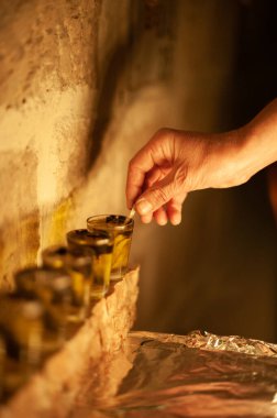 Closeup of a man's hand holding a wick and setting it in a vial of oil prior to lighting the Hanukkah menorah during the eight-day Festival of Lights in Israel.  clipart