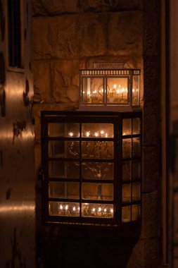 Glowing Hanukkah menorahs lit with small vials of oil burn in protective glass housing outside an apartment building in Jerusalem during the celebration of the Festival of Lights in Israel clipart