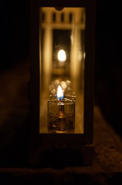 A glowing Hanukkah menorah lit with small vials of oil burns in protective glass housing outside a home in Jerusalem during the celebration of the Festival of Lights in Israel. clipart