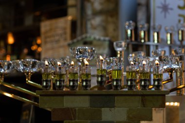 A glowing Hanukkah menorah lit with small vials of oil burns in a store in Jerusalem during the celebration of the Festival of Lights in Israel. clipart