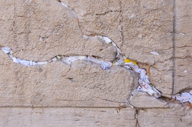 Tiny slips of paper with written prayers to God are inserted into the cracks of the Western Wall in Jerusalem, Israel.  clipart