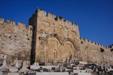 The medieval stone walls and ramparts of the Old City of Jerusalem and the cemetery and sealed twin arches of the Mercy Gate or Golden Gate with twin arches.  clipart