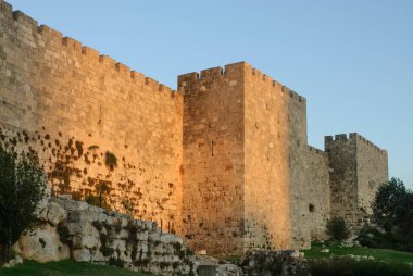 A section of the ancient stone ramparts and walls of the Old City of Jerusalem, bathed in golden light at twilight in Israel.  clipart