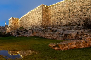 Akşam erken saatlerde Kudüs 'te alacakaranlıkta aydınlanan David Kulesi' nin batı duvarları ve Eski Şehrin surları.. 