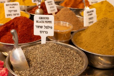 A variety of spice powders, including cumin, paprika, black pepper on sale in a spice stall in Jerusalem's Machane Yehuda outdoor market.  clipart