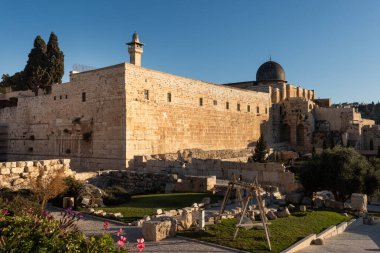 The western and southern walls below the Temple Mount with the  black domed Al-Aqsa Mosque in the background, the main congregational mosque in the Old City of Jerusalem, Israel. 	  