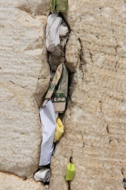 Tiny slips of paper with written prayers to God are inserted into the cracks of the Western Wall in Jerusalem, Israel.  clipart