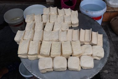 Taze basılmış tofu kekleri veya soya fasulyesi kartları Hanoi, Viet Nam 'da bir sokak pazarında toplu olarak satılıyor.. 