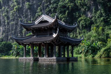 Budist dua ve ibadetlerinde kullanılan yüzen, ahşap bir tapınak Trang Nehri, Ninh Binh, Vietnam 'daki kireçtaşı kayalıklarıyla çevrili.. 