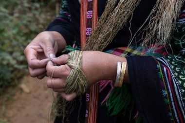 Geleneksel elbiseli bir Hmong kadınının, Kuzey Vietnam 'ın dağlarında kenevir lifleri dokuduğu bir kumaşa yakın plan.. 
