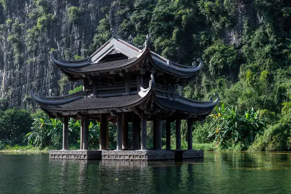 Budist dua ve ibadetlerinde kullanılan yüzen, ahşap bir tapınak Trang Nehri, Ninh Binh, Vietnam 'daki kireçtaşı kayalıklarıyla çevrili.. 