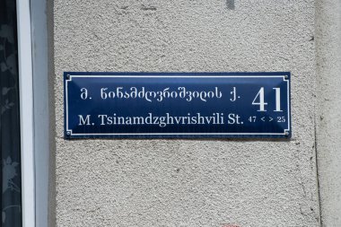 Gürcüce sokak levhası ve ismi İngilizce çevrilmiş, Tiflis, Gürcistan 'da bir beton duvara monte edilmiş.. 