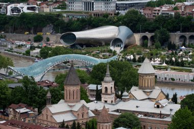 Gürcistan Cumhuriyeti 'nin başkenti Tiflis' in hava manzarası, şehir merkezinden geçen Kura Nehri boyunca uzanan modern cam yaya barış köprüsü.. 