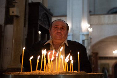 Worshippers light candles and recite prayers in the sanctuary of the Holy Trinity Cathedral in Tbilisi, Georgia.  clipart