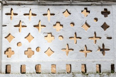 Whitewashed wall in Spain with cutouts in various shapes, sizes and symbols.  clipart