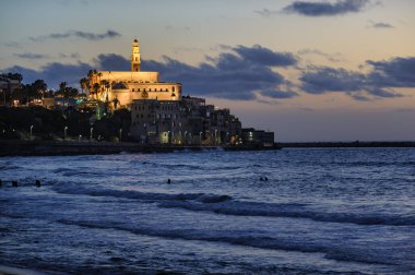 Tel-Aviv-Jaffa kıyı şeridinin alacakaranlık manzarası ve St. Peter Kilisesi akşam saatlerinde aydınlandı.. 