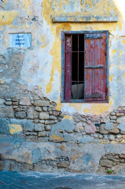 Yunanistan 'ın Rodos adasında eski, taş, harap olmuş, kırmızı, ahşap panjurlu bir bina.. 