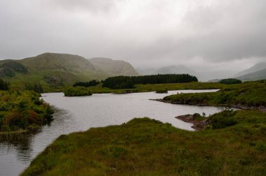 Fog and low clouds settle over a quiet, marshy stretch of rural western Ireland, County Galway.  clipart