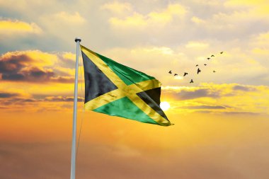 Jamaika bayrağını gün batımına ya da gün doğumuna karşı sallıyor. Cumhuriyet Günü ve Bağımsızlık Günü için Jamaika bayrağı.