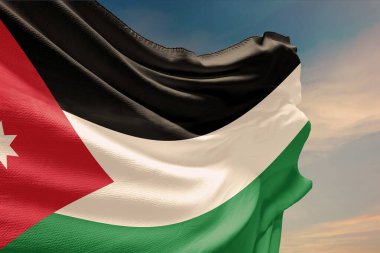 Mavi gökyüzünde Ürdün bayrağı sallıyor. Jordan Bağımsızlık Günü için direkte bayrak sallıyor. Devletin dalgalı kumaş üzerindeki sembolü..