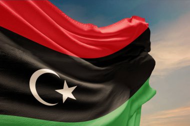 Mavi gökyüzünde Libya bayrağı sallıyor. Bağımsızlık Günü için Libya bayrağı direkte. Devletin dalgalı kumaş üzerindeki sembolü..