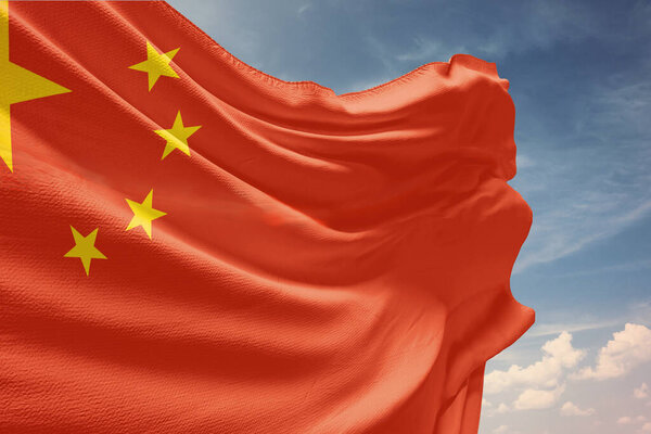 Размахивая флагом Китая в голубом небе. Флаг Китая на шесте ко Дню независимости. Символ государства на волнистой ткани.