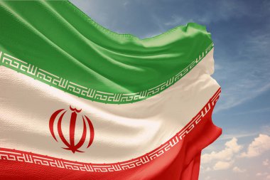 Mavi gökyüzü arka planında dalgalanan İran bayrağı.