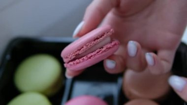 Açık pembe Fransız tatlısının yakın plan çekimini yapan bir kadın. İştah açıcı bir geçmiş. Yüksek kalite 4k görüntü. 