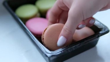 Altı paket badem kurabiyesi yeşil pembe ve çikolatalı kadın eli tatlıyı seçiyor. Yüksek kalite 4k görüntü