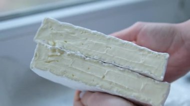 Tezgahın üzerinde peynir var. Camembert Brie peyniri pencere pervazında genç bir kızın elinde. Yüksek kalite 4k görüntü