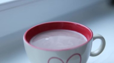 Kışa krema ekle Sıcak içecek bej bardağı içinde kırmızı renk çizilmiş kalp ile güzel bir tatlı pencerenin yanında rahatla. Yüksek kalite 4k görüntü