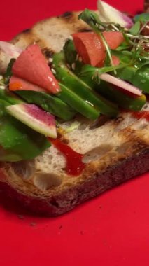 Sağlıklı yiyecekler. Avokado ve çilekli ekmekli tost, yakın çekim. Fırınlanmış kireçle birlikte parlak kırmızı bir tabakta.