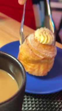 Lokanta kadınlarının elinde, kahve ve kaşıkla mavi bir tabakta şekerleri ayarlayan katmanlı tatlı servisi. Yüksek kalite 4k görüntü